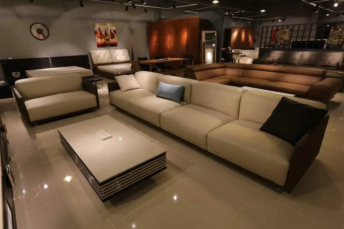 Cream-colored leather sectional sofa with dark wood frame and black and blue pillows ideal for bonus room square footage.