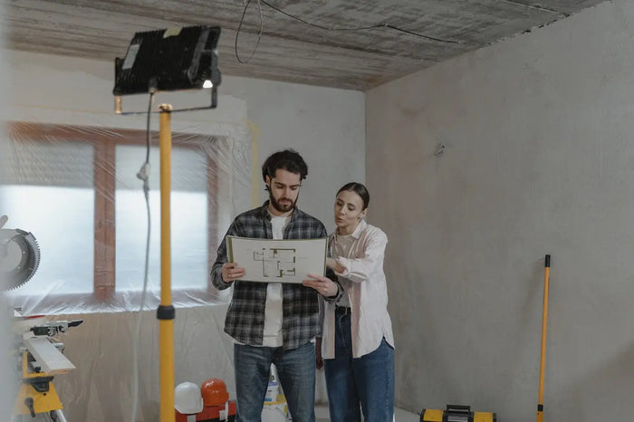 A man and woman review architectural blueprints during a home remodel to avoid common mistakes with a remodeling contractor.