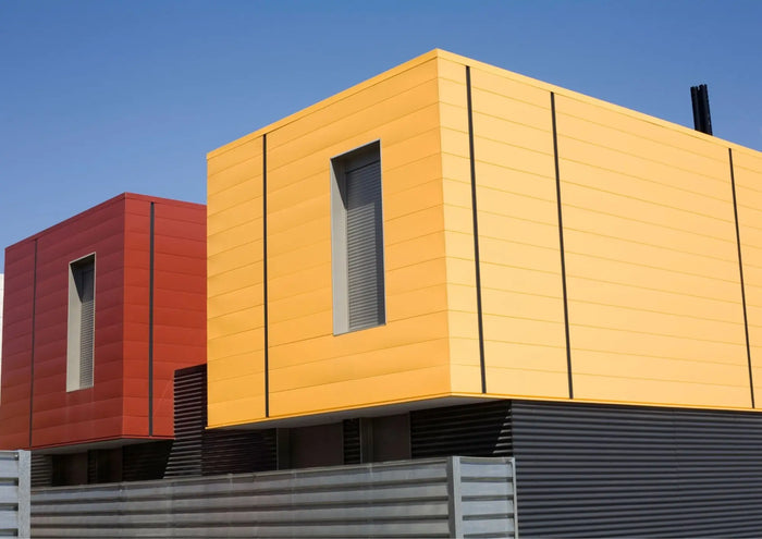 Modern prefabricated modular home with yellow and red geometric design featuring horizontal siding panels.