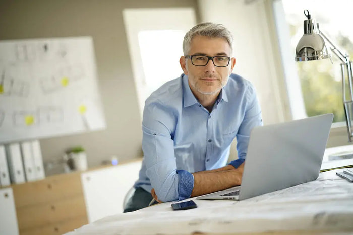 A silver laptop with a minimalist design sits open on a desk for architects to draw plans and site plans.