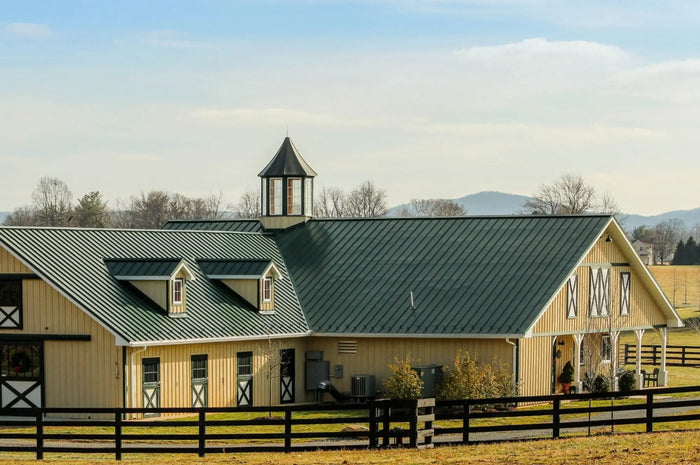 Beige wooden barndominium with green metal roofing and white cross-patterned doors showcasing barndominium pros site plan
