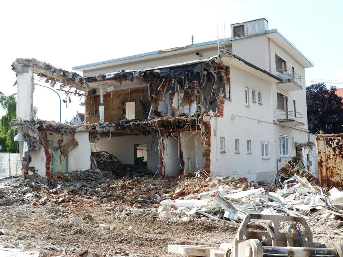 A partially collapsed white building with exposed brick and rubble illustrating demolition work requiring a demolition permit.