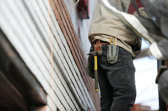 Yellow-handled hammer in black leather tool holster for contractors aiding site plan and building codes compliance