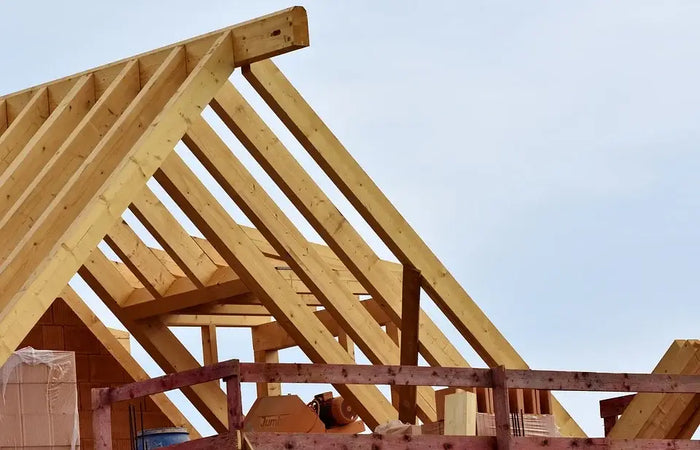 Light-colored wooden roof trusses forming triangular structure used in house framing with platform and balloon framing methods