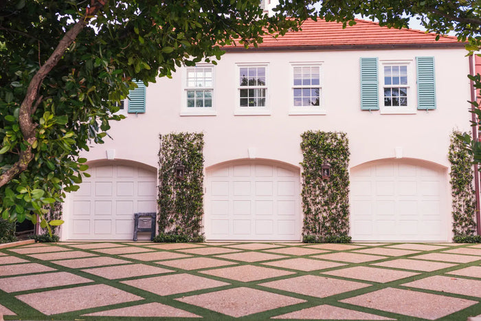 A white garage door with an arched top and vertical panels flanked by ivy-covered pillars for adu garage conversion site plan