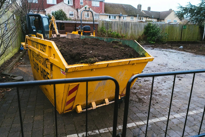 Yellow metal skip bin filled with dark soil illustrating dirt removal and dirt disposal solutions in construction waste management