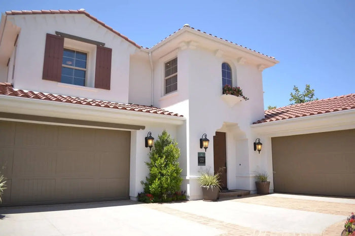White stucco mediterranean-style house with terracotta roof and brown shutters showcasing a garage addition site plan.