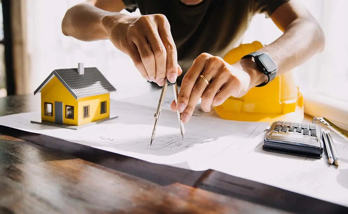 Yellow miniature house model with black roof and gray door representing site plan partner in contracting business article