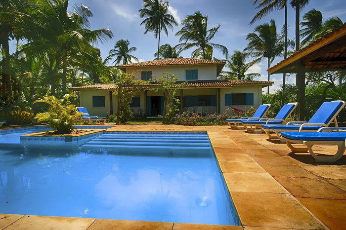 Blue lounge chairs with white metal frames on a tiled patio by an inground pool for pool removal preparation