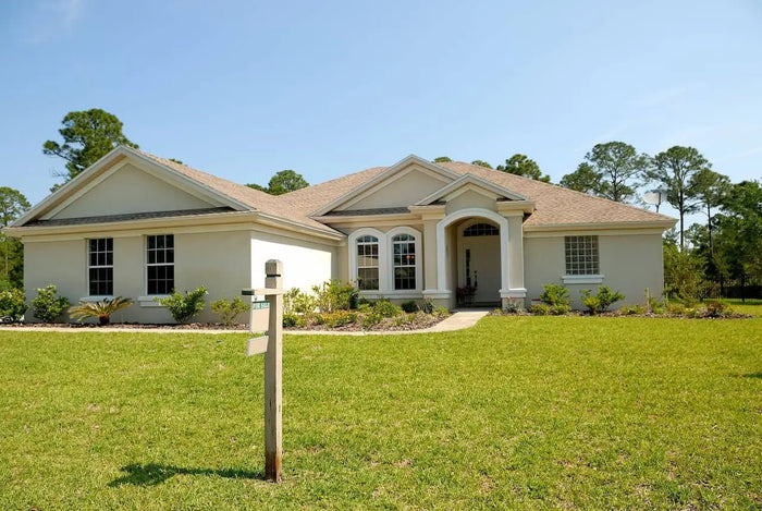Beige stucco house with brown shingled roof and white trim illustrating plot plan and land survey differences
