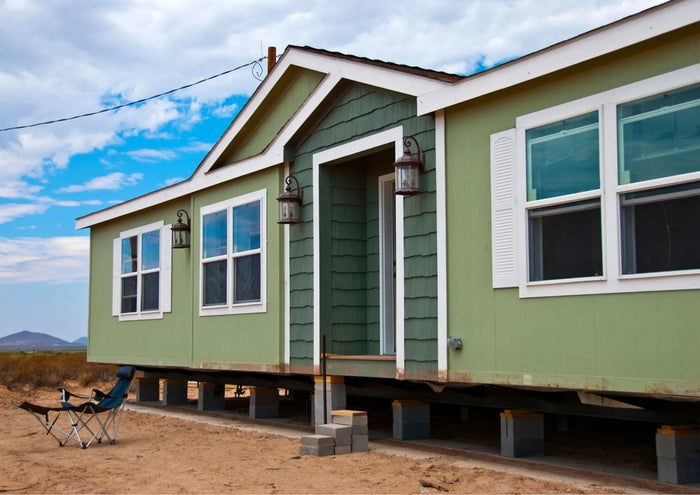 A light green prefabricated home with white trim and gabled roof illustrating key features of prefab homes.