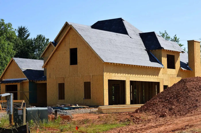 Unfinished two-story house with yellowish-brown wooden framing and dark gray roofing illustrating a foundation plan with crawl space
