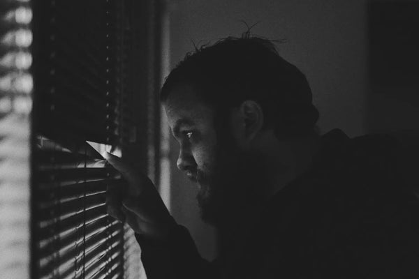 A man peeking through blinds