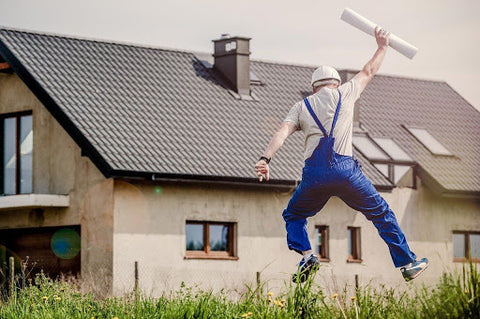 man holding up a plan in front of a house