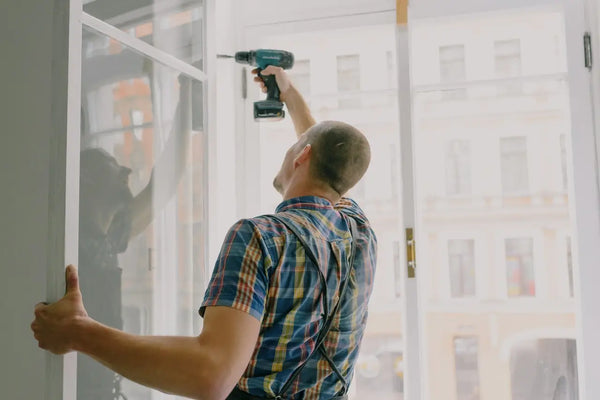 Homeowner installing window frame with drill in house