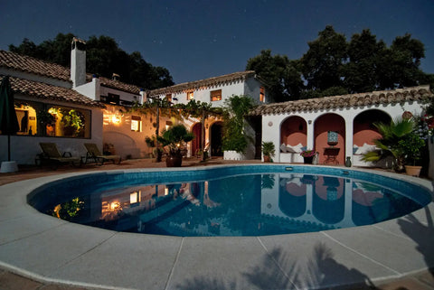 backyard pool at night with outdoor lights
